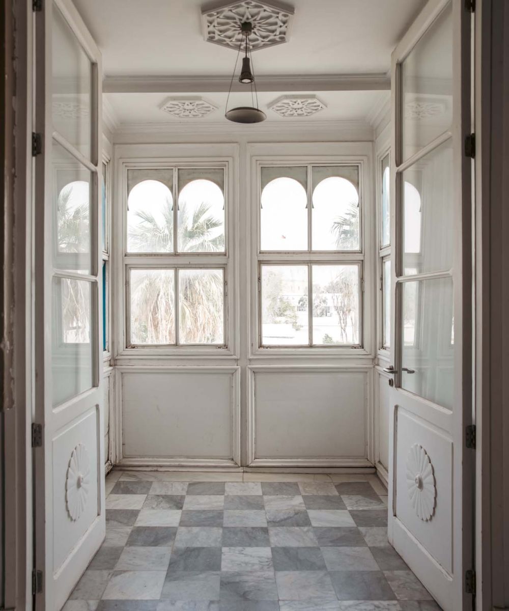view of an entrance with tall open doors and arched windows with patterned grey and white floor